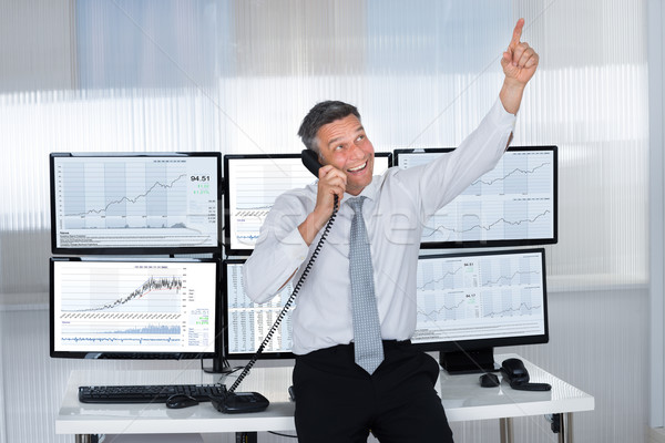 Happy Stock Trader Pointing Upwards While Using Telephone Stock photo © AndreyPopov