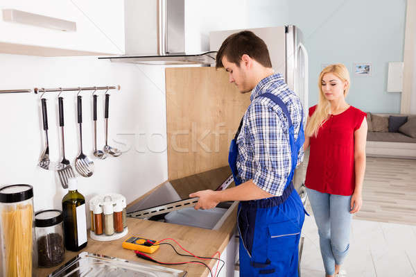 Stock photo: Repairman Examining Stove In Kitchen