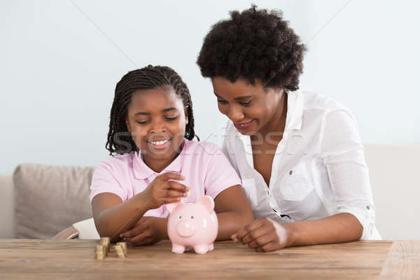 Girl With Mother Inserting Coins In Piggy Bank Stock photo © AndreyPopov