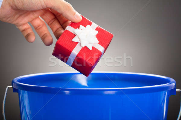Businessman's Hand Throwing Gift Box In Blue Bucket Stock photo © AndreyPopov