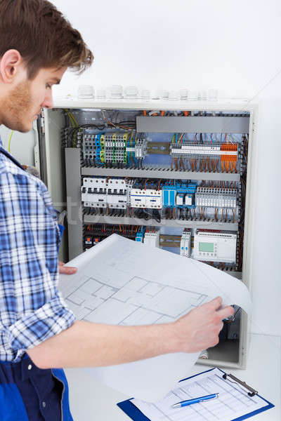 Technician Analyzing Blueprint In Front Of Fusebox Stock photo © AndreyPopov