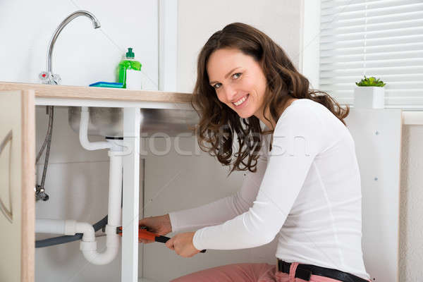 Woman Fixing Pipe With Adjustable Wrench Stock photo © AndreyPopov