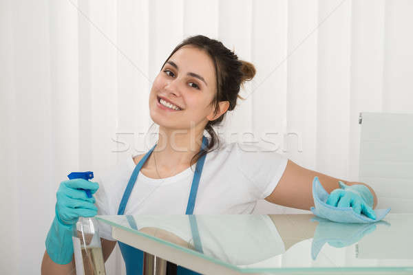 Female Janitor Using Spray To Wipe Desk Stock photo © AndreyPopov