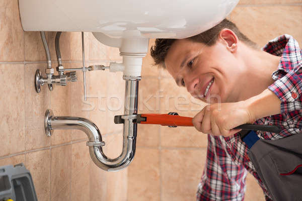 Vízvezetékszerelő megjavít mosdókagyló cső franciakulcs mosolyog Stock fotó © AndreyPopov