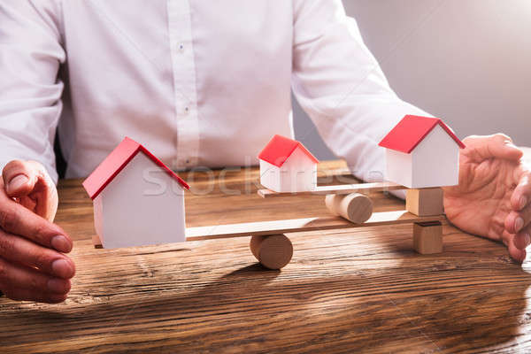 Businessperson's Hand Covering Balance Between House Models Stock photo © AndreyPopov