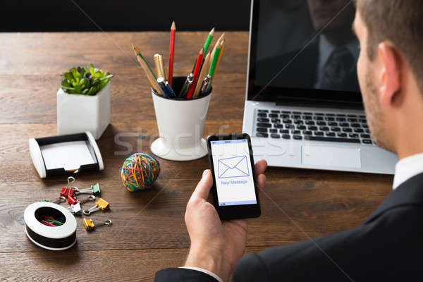 Businessman Looking At New Message On Mobile Phone Stock photo © AndreyPopov