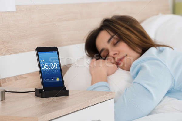 Woman Sleeping On Bed With Alarm On Mobile Phone Stock photo © AndreyPopov