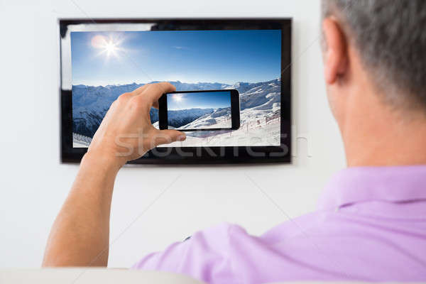 Man With Smartphone Connected To A TV Watching Movie Stock photo © AndreyPopov