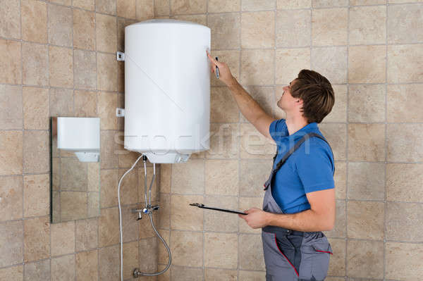 Male Plumber Holding Clipboard Checking Electric Boiler Stock photo © AndreyPopov
