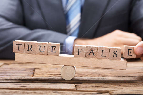 Stock photo: Businessman With True And False Wooden Blocks On Seesaw