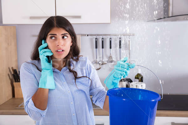 Woman Calling Plumber While Collecting Water Stock photo © AndreyPopov