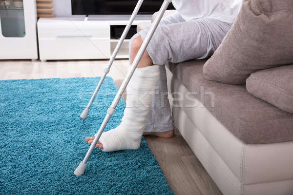 Om picior rupt in sus canapea tânăr carje Imagine de stoc © AndreyPopov
