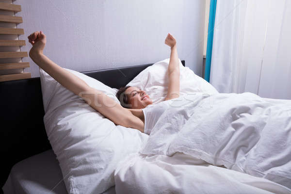 Woman Stretching Her Hands On Bed Stock photo © AndreyPopov