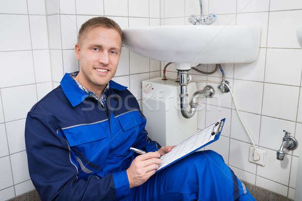 Young Plumber Writing On Clipboard Stock photo © AndreyPopov