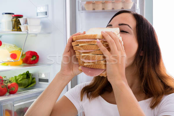 Woman Eating Sandwich In Front Of Refrigerator Stock photo © AndreyPopov
