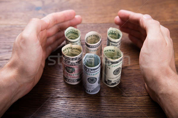 Hands Protecting The Rolled Up Currency Notes Stock photo © AndreyPopov