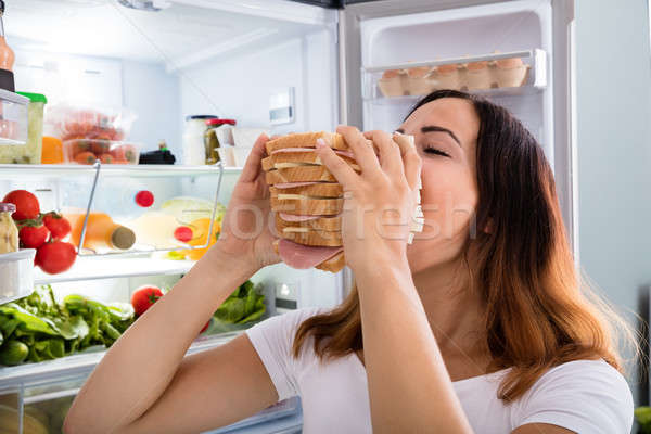Woman Eating Sandwich In Front Of Refrigerator Stock photo © AndreyPopov