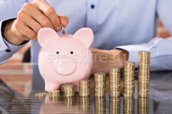 Businessman Insert Coins In Piggy Bank Stock photo © AndreyPopov