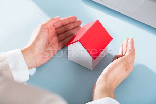 Businesswoman's Hand Protecting Miniature House Stock photo © AndreyPopov