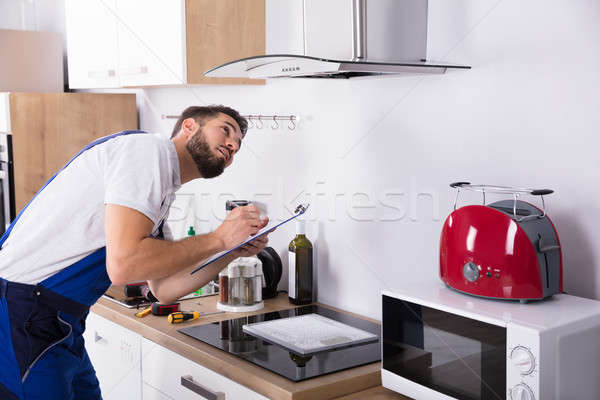 Technician Writing On Clipboard In Front Of Kitchen Extractor Stock photo © AndreyPopov