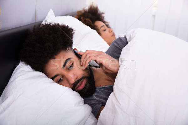 Człowiek mówić telefonu komórkowego żona snem bed Zdjęcia stock © AndreyPopov