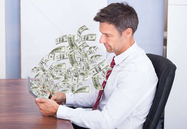 Businessman Looking At Money Coming Out Of Digital Tablet Stock photo © AndreyPopov