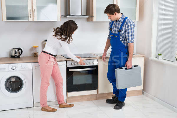 Housewife Showing Damaged Oven To Worker Stock photo © AndreyPopov