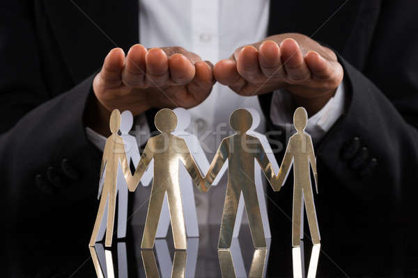 Businessperson Protecting Cut-out Figures Stock photo © AndreyPopov