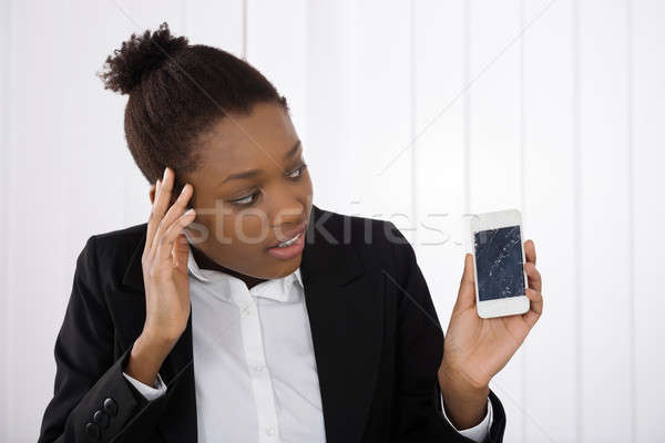 Stock photo: Worried Businesswoman Holding Smartphone With Cracked Screen
