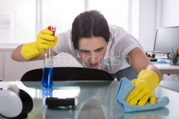 Female Janitor Cleaning Desk In Office Stock photo © AndreyPopov