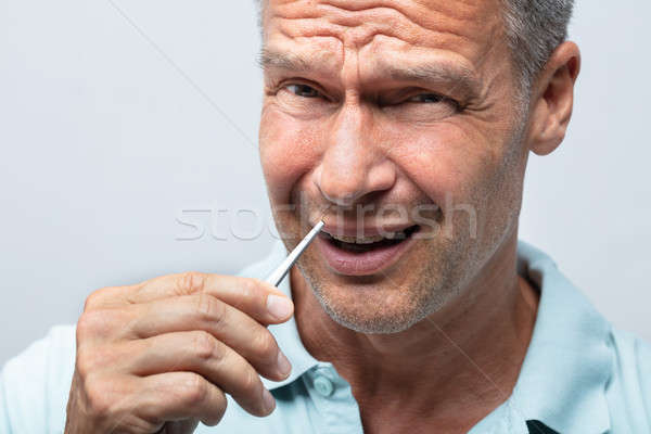 Man In Pain Removing Nose Hair With Tweezers Stock photo © AndreyPopov