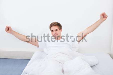 Young Man Stretching In Bed Stock photo © AndreyPopov