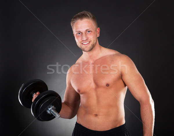 Young man working out lifting weights in a gym Stock photo © AndreyPopov