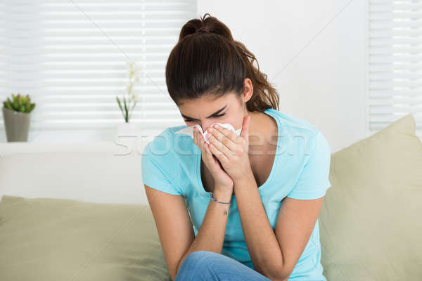 Kobieta dmuchanie nosa sofa domu chorych młoda kobieta Zdjęcia stock © AndreyPopov