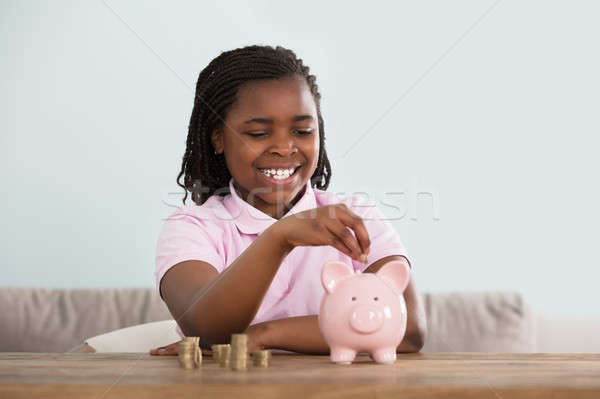Girl Inserting Coins In Piggy Bank Stock photo © AndreyPopov