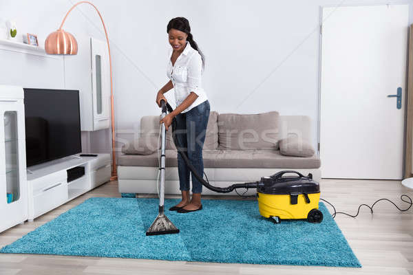 Kobieta czyszczenia dywan odkurzacz młodych Afryki Zdjęcia stock © AndreyPopov
