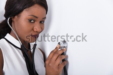 Woman Placing Stethoscope On Wall Stock photo © AndreyPopov