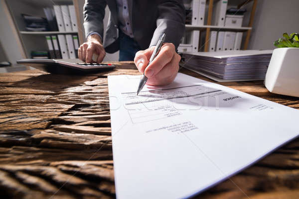 Businessperson Using Calculator While Signing Document Stock photo © AndreyPopov