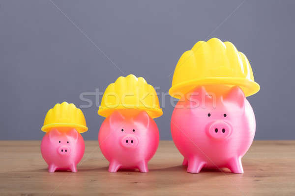 Increasing Pink Piggy Banks With Yellow Hard Hat Stock photo © AndreyPopov