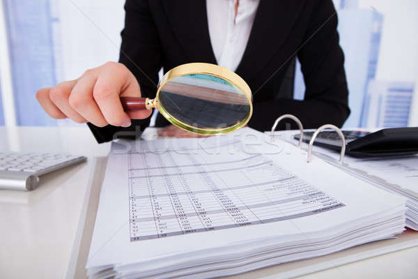 Businesswoman Scrutinizing Bills With Magnifying Glass Stock photo © AndreyPopov