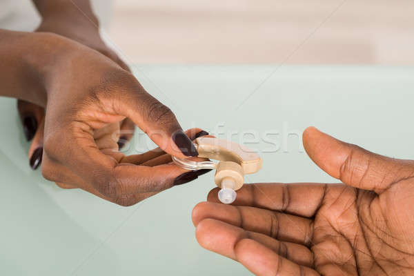 Doctor's Hand Giving Hearing Aid To Patient Stock photo © AndreyPopov