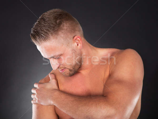 Stock photo: Muscular sportsman massaging his shoulder