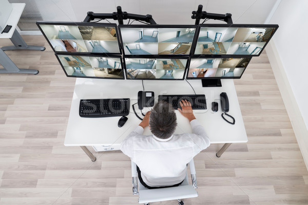 Security System Operator Looking At CCTV Footage At Desk Stock photo © AndreyPopov