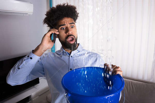 Man Calling Plumber While Leakage Water Falling Into Bucket Stock photo © AndreyPopov