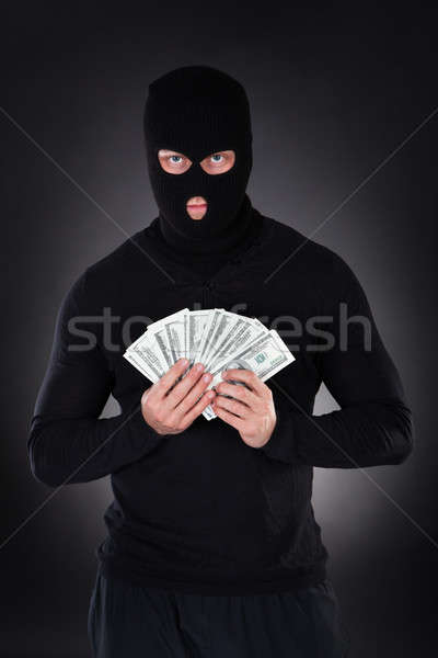 Criminal in a balaclava holding a fistful of money Stock photo © AndreyPopov