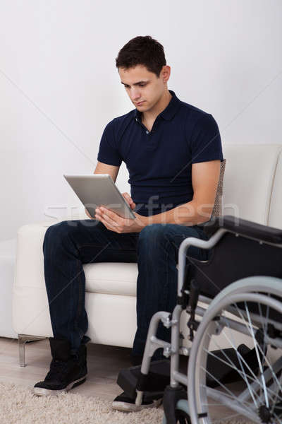 Handicapés homme numérique comprimé canapé [[stock_photo]] © AndreyPopov