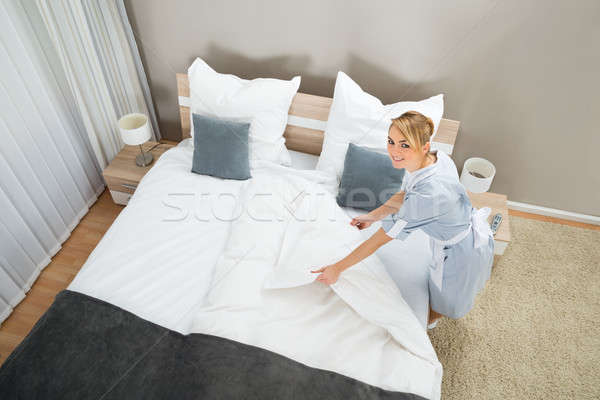 Female Housekeeper Making Bed With Bed Clothes Stock photo © AndreyPopov