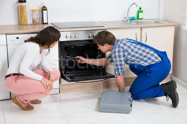 Woman Looking At Worker Repairing Oven Stock photo © AndreyPopov