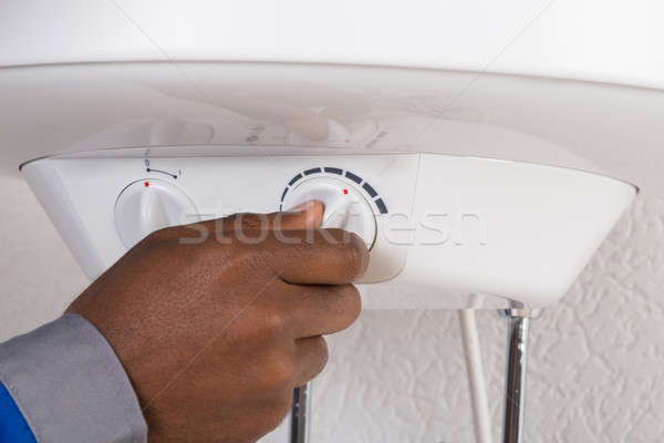 Plumber's Hand Turning The Knob Of Electric Boiler Stock photo © AndreyPopov