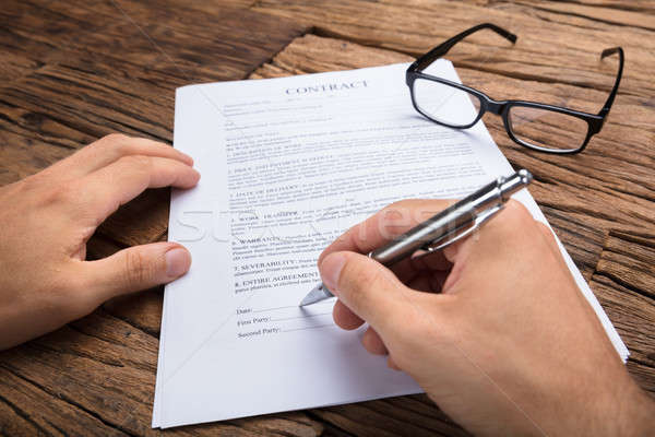 Stock photo: Businessman's Hands Signing Contract At Wooden Table